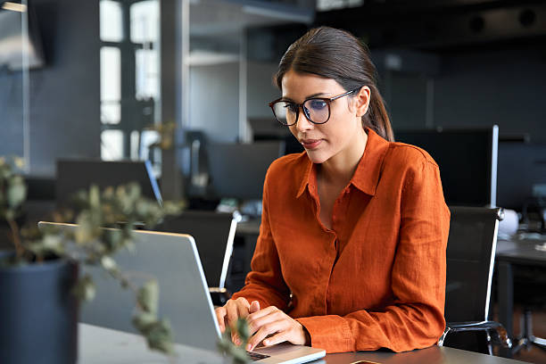 istock European mature woman in eyeglasses using computer for finance data analysing work online. Focused financial specialist latin hispanic businesswoman working on laptop pc sitting at desk in office. 2219519847
