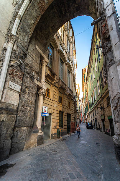 Genoa, Liguria, Italy - June 01, 2025: Via del Campo with Porta dei Vacca is one of the things to see in the alleys of the Historic Center of Genoa, a paved street that crosses the caruggi or alleys of the historic center of Genoa in a transverse direction