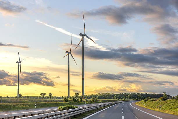 istock Wind turbines at sunset. Road and clean energy 2219527340