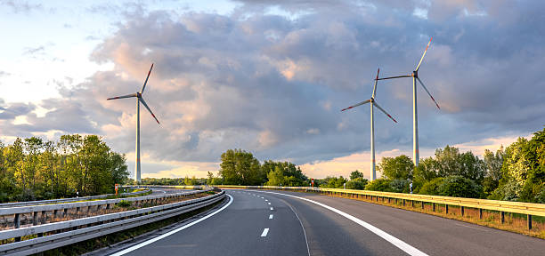 istock Wind turbines by highway. Eco travel. Scenic infrastructure 2219527344