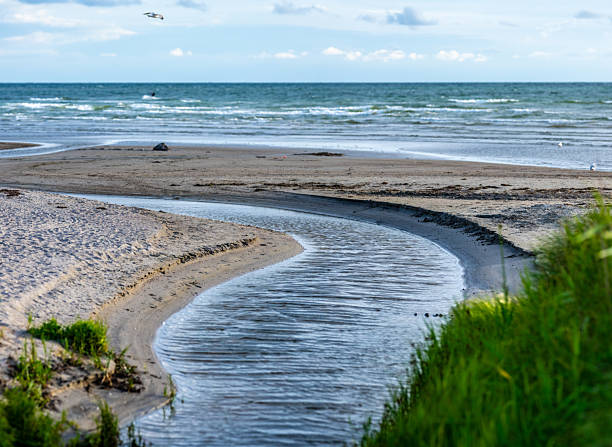 curved waterway leading to ocean at beach.