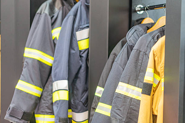 istock Three olive green firefighter jackets with reflective stripes, hung in a locker room setting, featuring chest pockets and zipper closures, possibly representing a team or department 2219532605