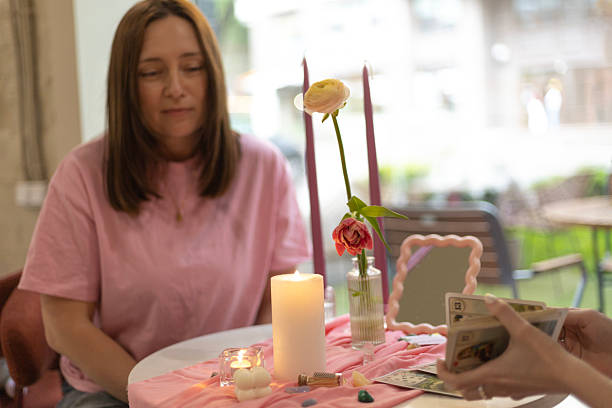A calm moment during a tarot reading session: client and tarot reader connect at a cozy pink-toned table, full of mystical ambiance.