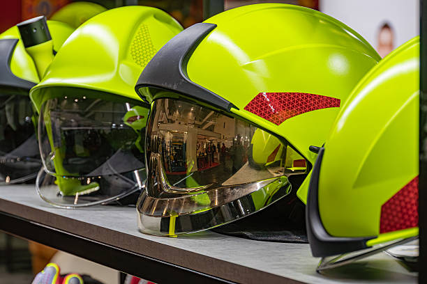istock Bright yellow firefighter helmets lined up against a store display wall, arranged left to right Clear visors reflecting environment Organized presentation with angled perspective Hint of blurred p 2219532968