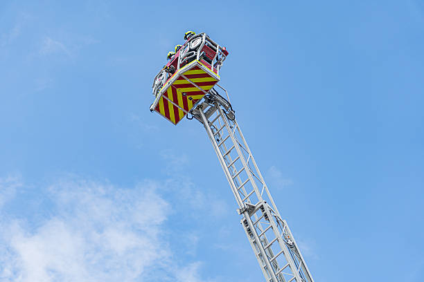 istock Fire engine with extended ladder, firefighter in protective gear, daytime lighting, clear sky, candid shot, emergency response exercise or training 2219533572