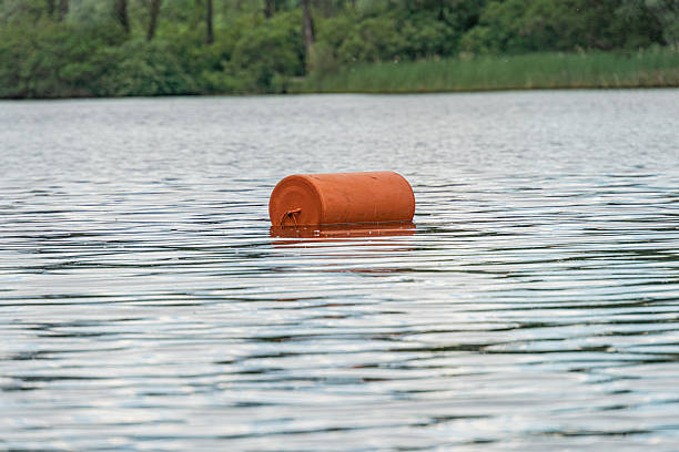 istock Centered orange buoy floating on calm, reflective water in a tranquil lake or river setting Subdued colors contrasting against the vibrant buoy No other objects or people visible 2219534160