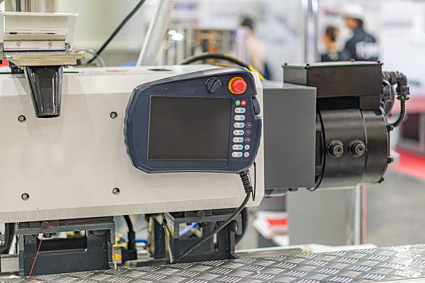 istock Industrial setting, large mechanical device with controls and display screen, possibly used for manufacturing or processing Two bystanders in background Even lighting, neutral color palette No tex 2219534416