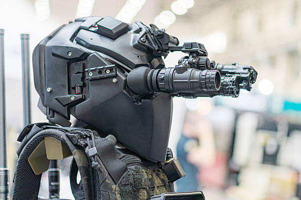 Close-up image of a sleek black, advanced humanoid robot with mechanical joints, holding a high-tech weapon Setting suggests a robotic or defense technology exhibition