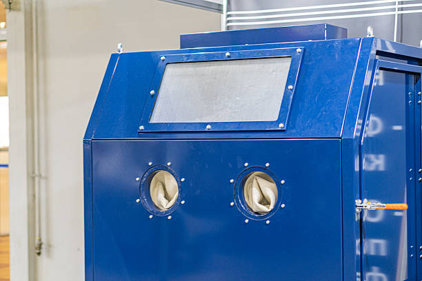 istock Blue machine with a closed, secure access panel Possible handles or locking mechanisms nearby Surrounding smaller blue component Visible screws suggest assembly and potential maintenance Dimly li 2219535422