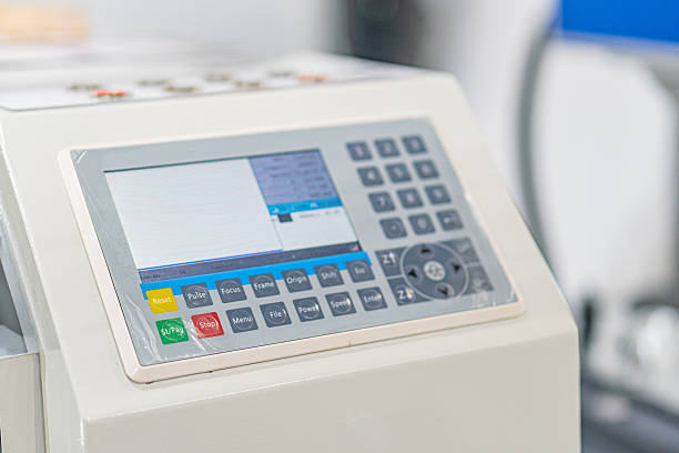 istock Off-center image of an industrial machine with a digital control panel The control panel is white and blue, containing numerous buttons in rows, with a green and red switch standing out Surrounding 2219535465