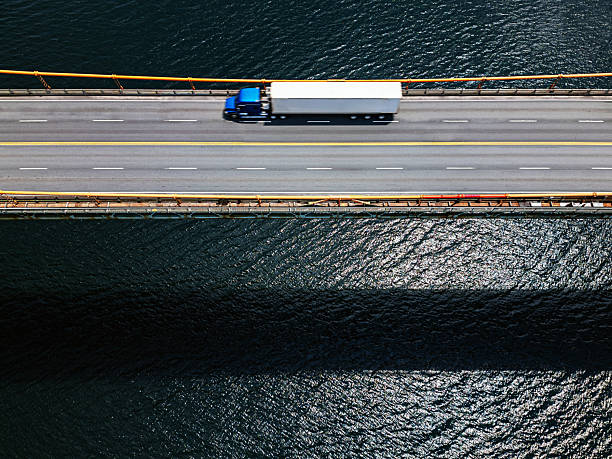Aerial view of a semi truck crossing a suspension bridge.