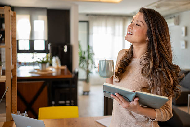 istock Young woman relaxing at home, drinking coffee and reading a book 2219543597