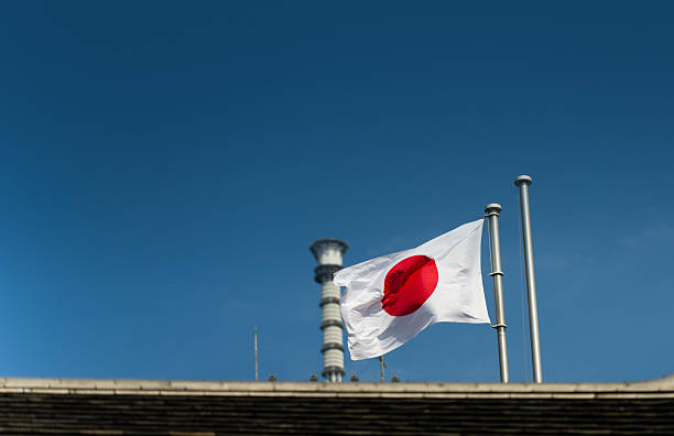 Japanese Flag Against Blue Sky with Tower