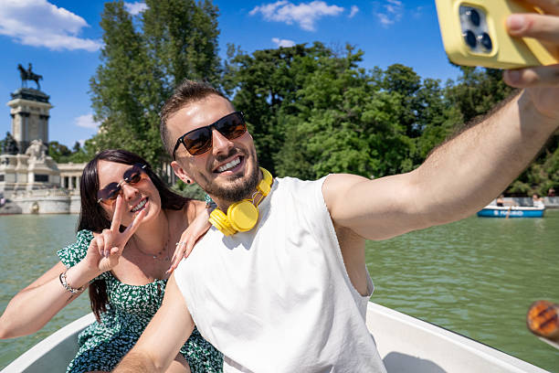 Happy tourists enjoying a boat ride in retiro park, madrid, taking a selfie to remember their vacation