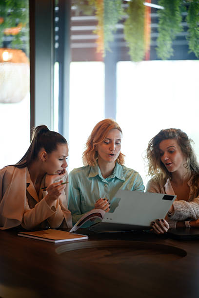 istock Three businesswomen collaborate on a project, reviewing information on a laptop while working at a table in a modern office space in the afternoon 2219557307