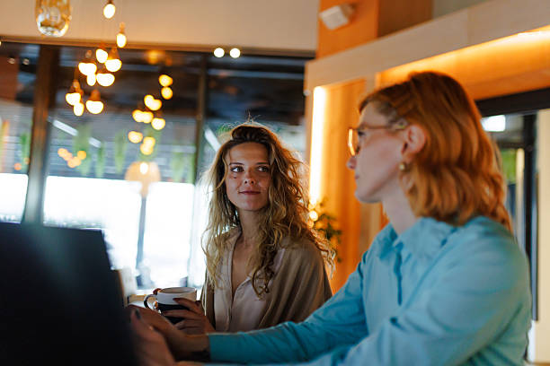 istock Business discussions between two women at a modern cafe during the day, highlighting collaboration and professionalism in a relaxed atmosphere 2219557329