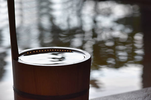A wooden bath bucket placed on the edge of the bathtub