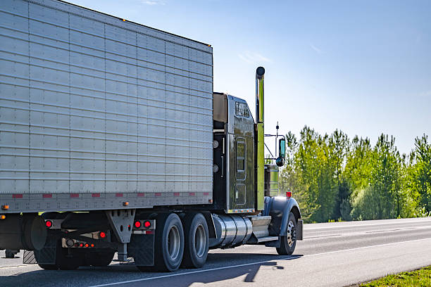 istock Black classic powerful big rig semi truck transporting cargo in refrigerator semi trailer running on the flat highway road 2219567580
