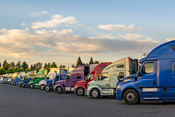 Professional carriers big rig semi trucks with semi trailers standing in row on truck stop parking lot taking a break stock photo