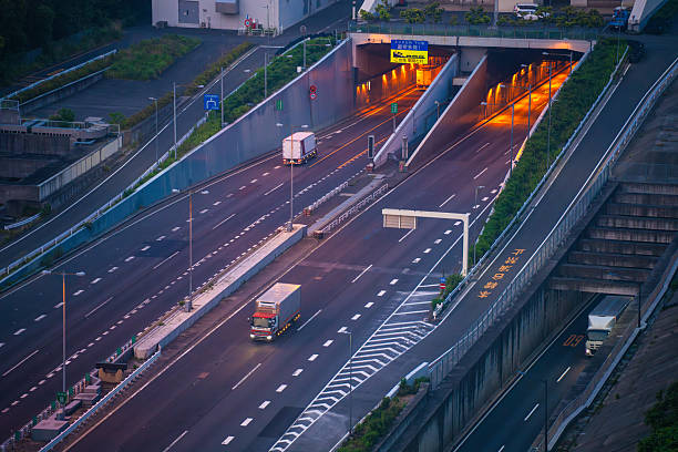 Trucks entering elevated tunnel on Japanese highway system during early evening blue hour
