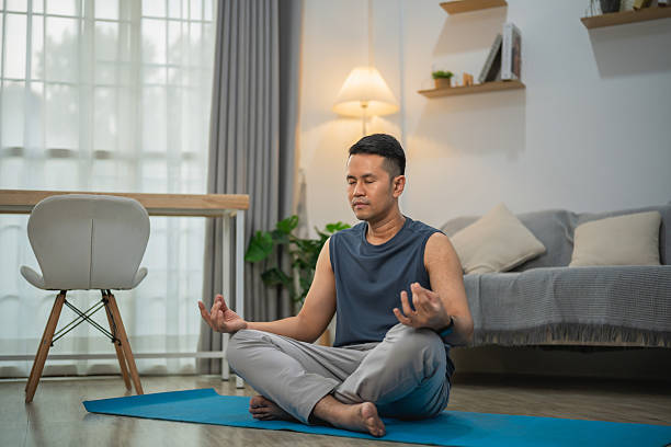 istock Man Practicing Mindfulness Meditation in a Modern Living Room with Natural Light, Focus on Relaxation and Inner Peace, Wellness Concept 2219576971