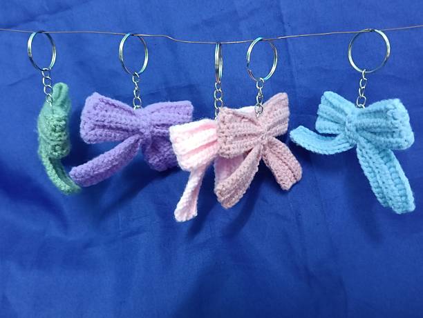 istock Handmade Crochet Keychains with Bow Designs hanging on blue Fabric Background 2219584569