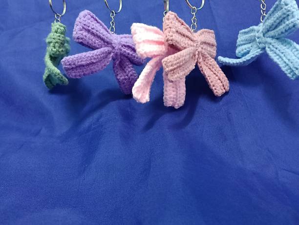 istock Handmade Crochet Keychains with Bow Designs hanging on blue Fabric Background 2219584597