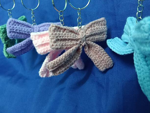 istock Handmade Crochet Keychains with Bow Designs hanging on blue Fabric Background 2219584632
