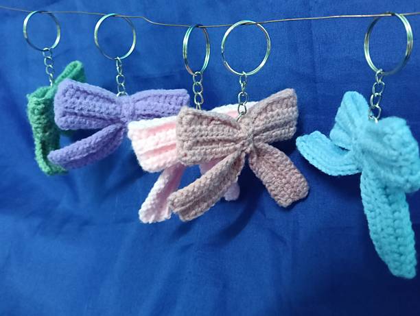 istock Handmade Crochet Keychains with Bow Designs hanging on blue Fabric Background 2219584689
