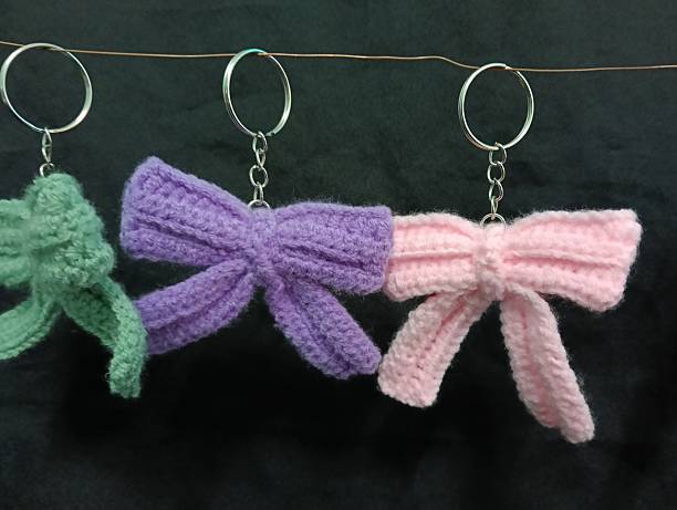 istock Handmade Crochet Keychains with Bow Designs hanging on Dark Fabric Background 2219584705