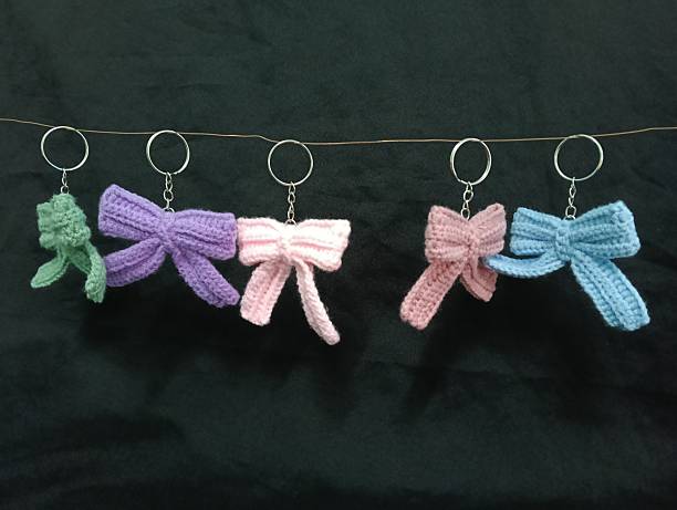 istock Handmade Crochet Keychains with Bow Designs hanging on Dark Fabric Background 2219584713