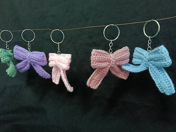 Handmade Crochet Keychains with Bow Designs hanging on Dark Fabric Background
