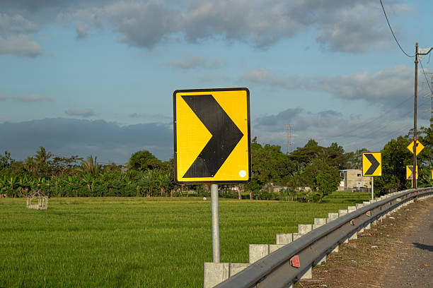 istock Sharp Turn Ahead Road Sign - Guiding Direction in Rural Landscape 2219586871