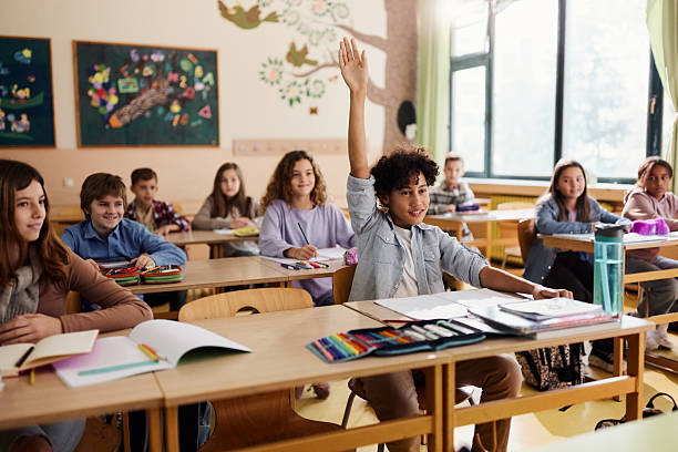istock Happy black elementary student raising his hand on a class at school. 2219587271