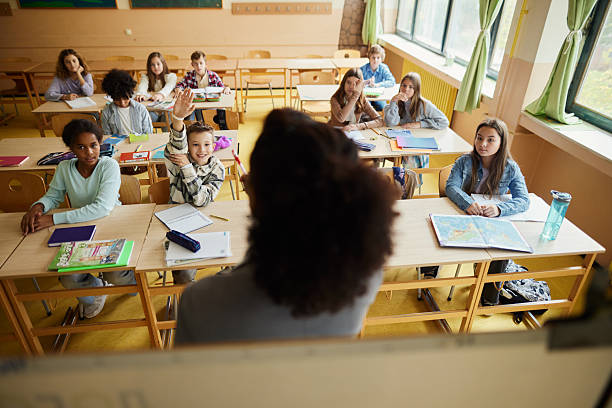 istock Happy schoolboy raising his hand on a class at school. 2219587785