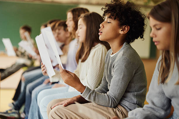 istock School kids practicing with sheet music on a class at school. 2219587858