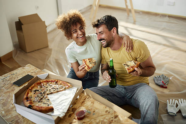 istock Cheerful couple having fun while eating pizza at their renovating apartment. 2219589126