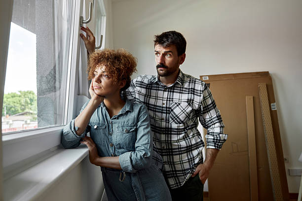 istock Thoughtful couple looking through window at their new apartment. 2219589408