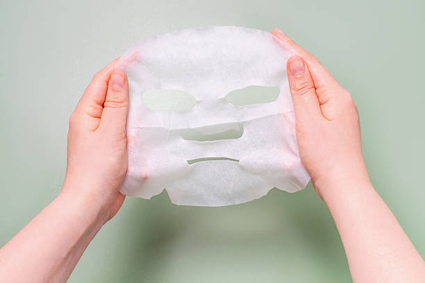 istock Female hands holding moisturizing mask sheet close-up on green background. 2219589862