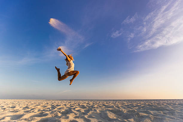 istock Carefree woman having fun while jumping on the beach. 2219590283