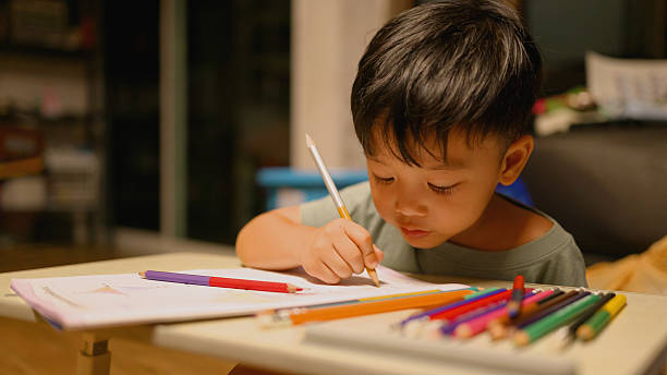 istock Asian Kindergarten Boy Coloring Homework After School – Creative Learning Concept. 2219591406