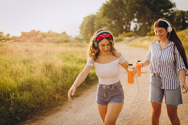 Portrait of two young cheerful female friends roller skating together in nature during the sunny day