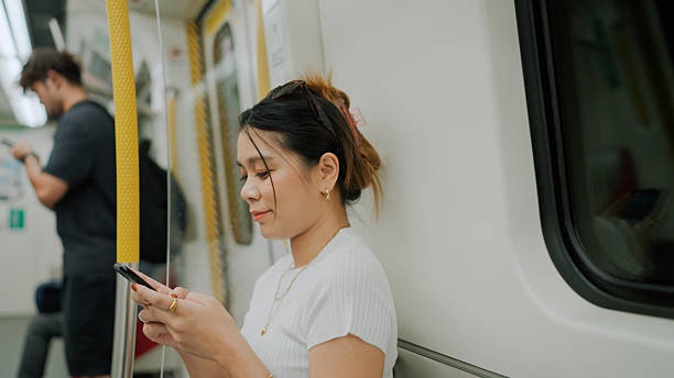 istock Young Asian woman sending text message to friend while sitting in a subway train. 2219593367