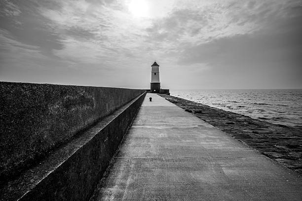 Monotone view of diminishing perspective along concrete causeway leading to lighthouse
