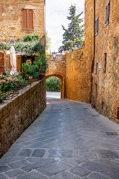 Quaint alleyway with rustic stone buildings in the historic village of Pienza, Tuscany, Italy.