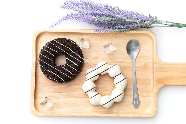Flat lay composition of tree black and white doughnuts on wooden tray.