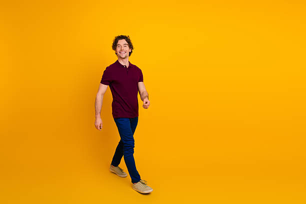istock Casually dressed man walking confidently with a cheerful expression against a vibrant yellow background 2219607659