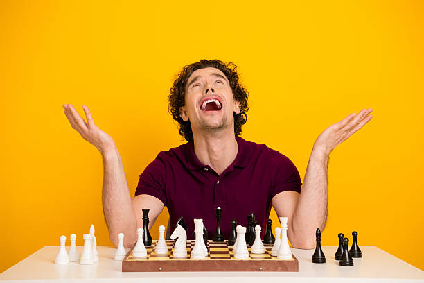istock Joyful man celebrates chess victory in a bright yellow background while energetically gesturing at a game board 2219607721