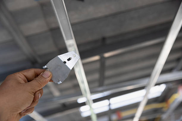Worker is using  locking keys to lock top cross rails to furring channels in concealed ceiling
