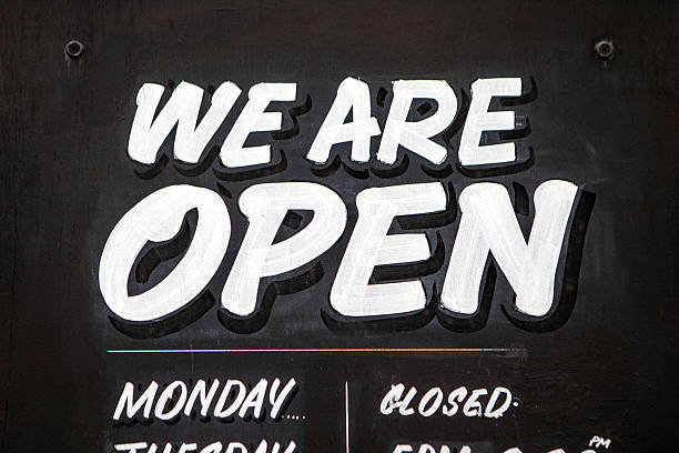 istock Hand painted shop opening times on a black board 2219610360